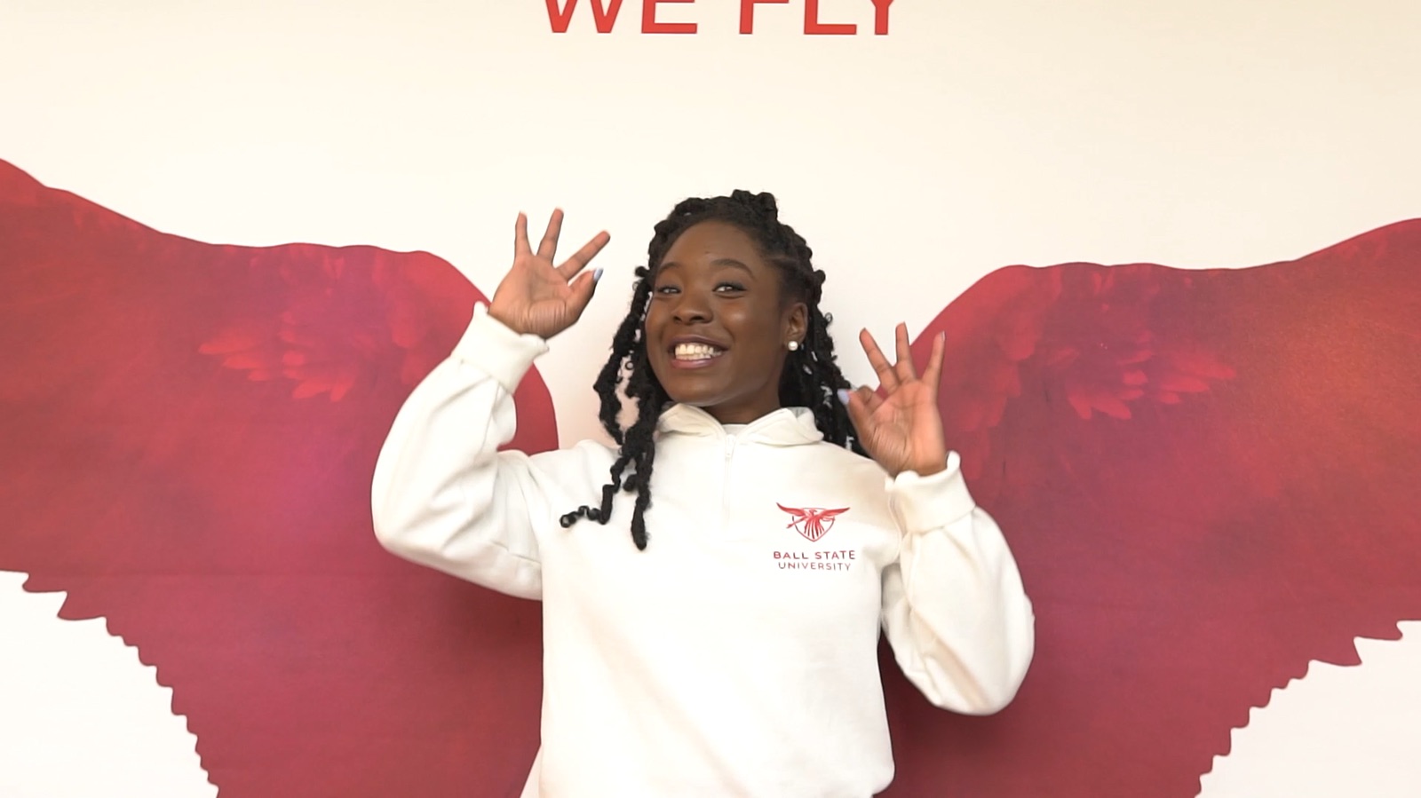 Graduate posing in front of red We Fly wings