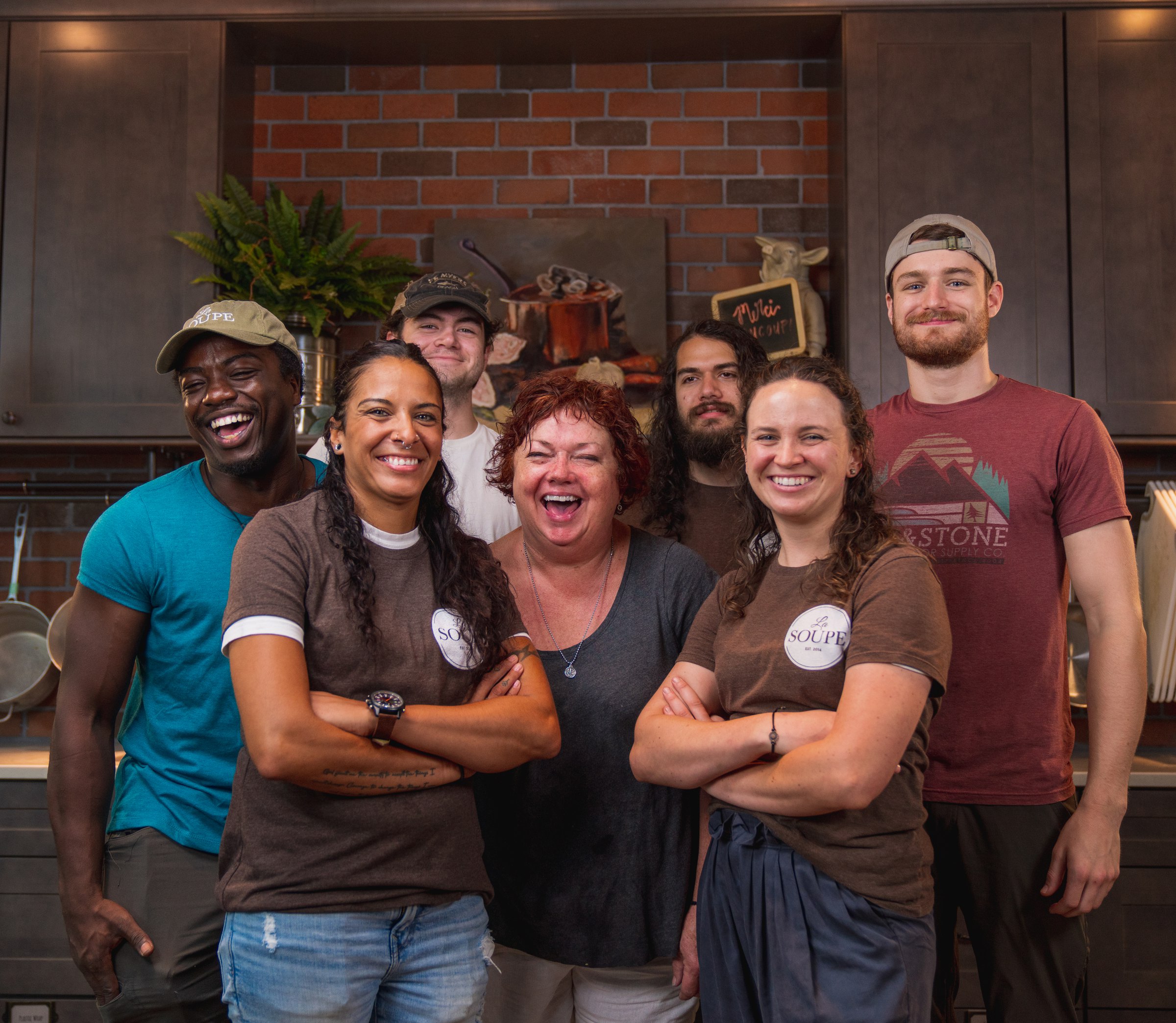 Seven La Soupe staff and volunteers grouped together and laughing in the kitchen