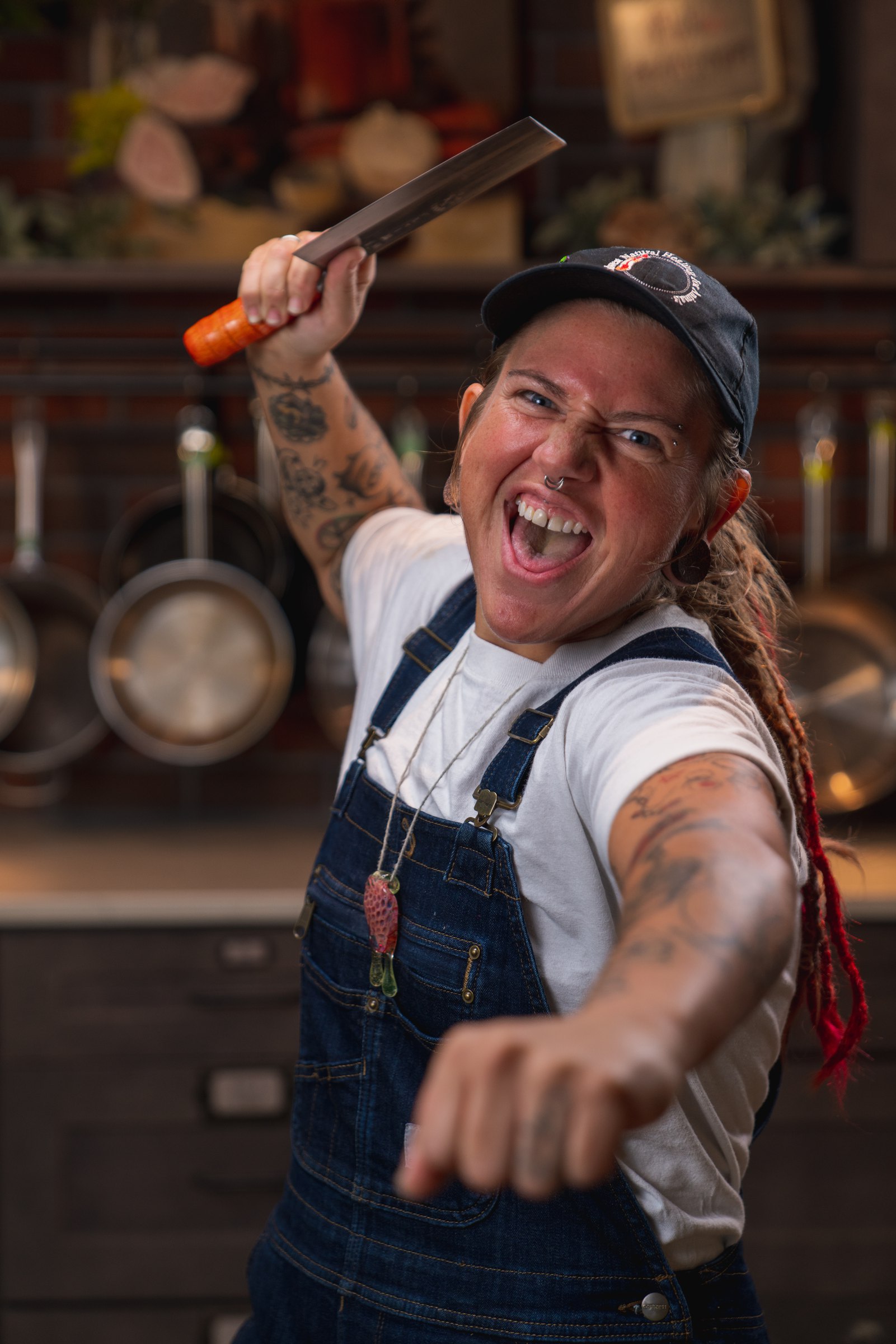 Cook in overalls lunging toward the camera with a cleaver raised