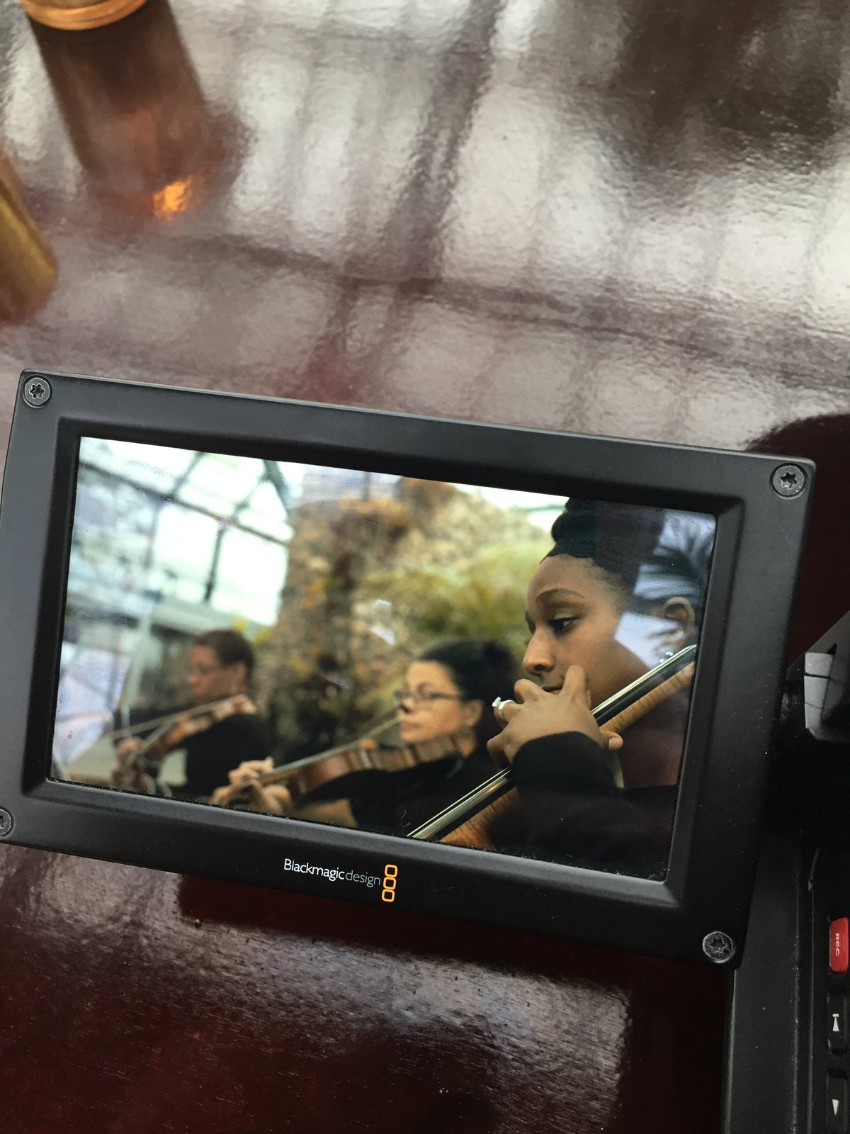 Camera monitor showing violinists playing at a wedding
