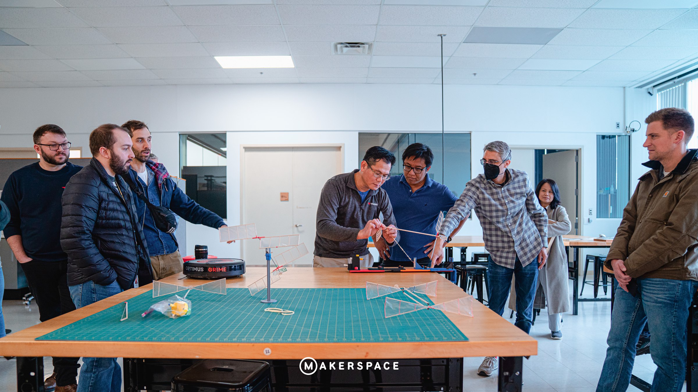 Engineers gathered around a table of balsa gliders