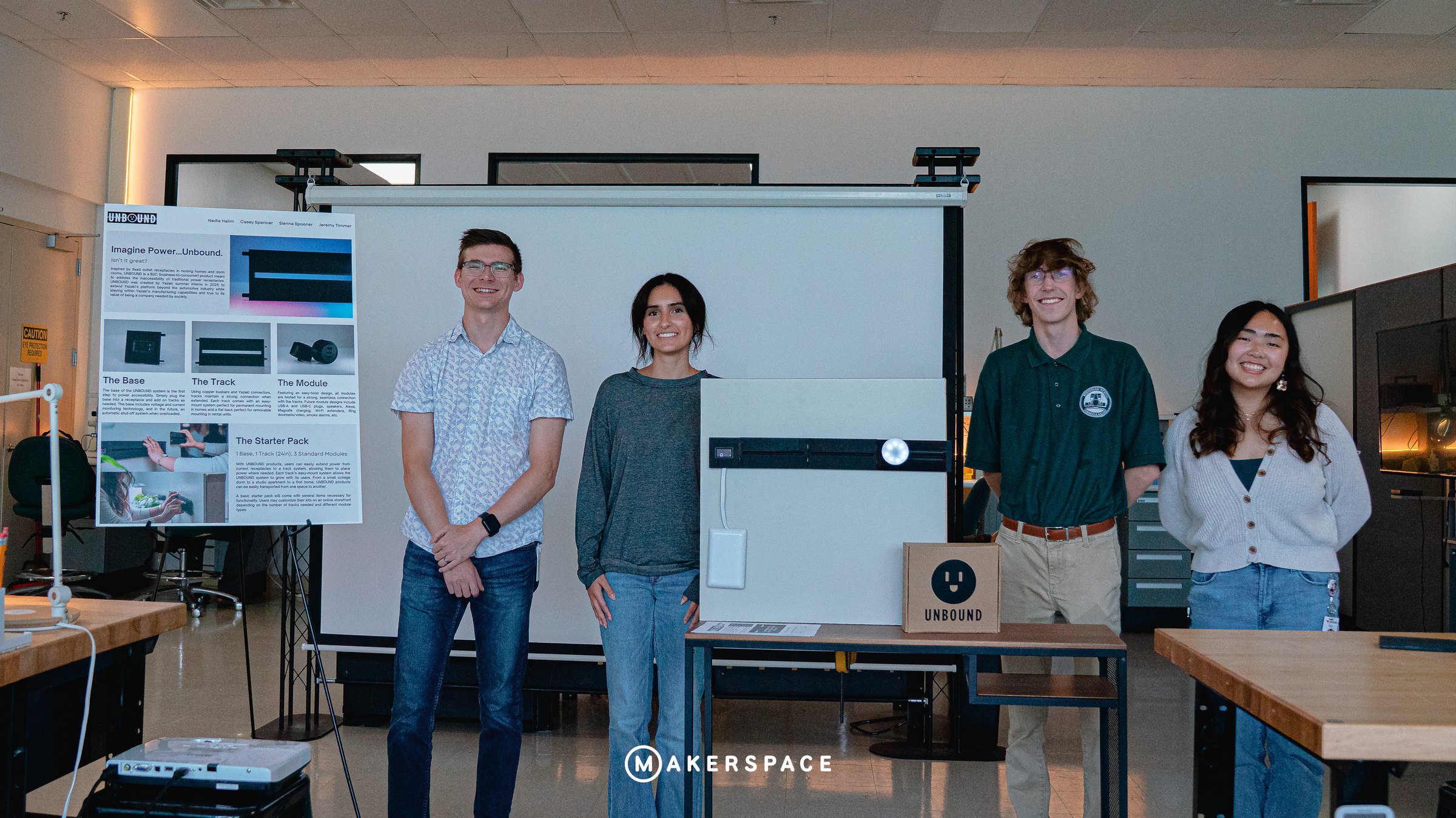 Four interns beside their UNBOUND power-track prototype and poster