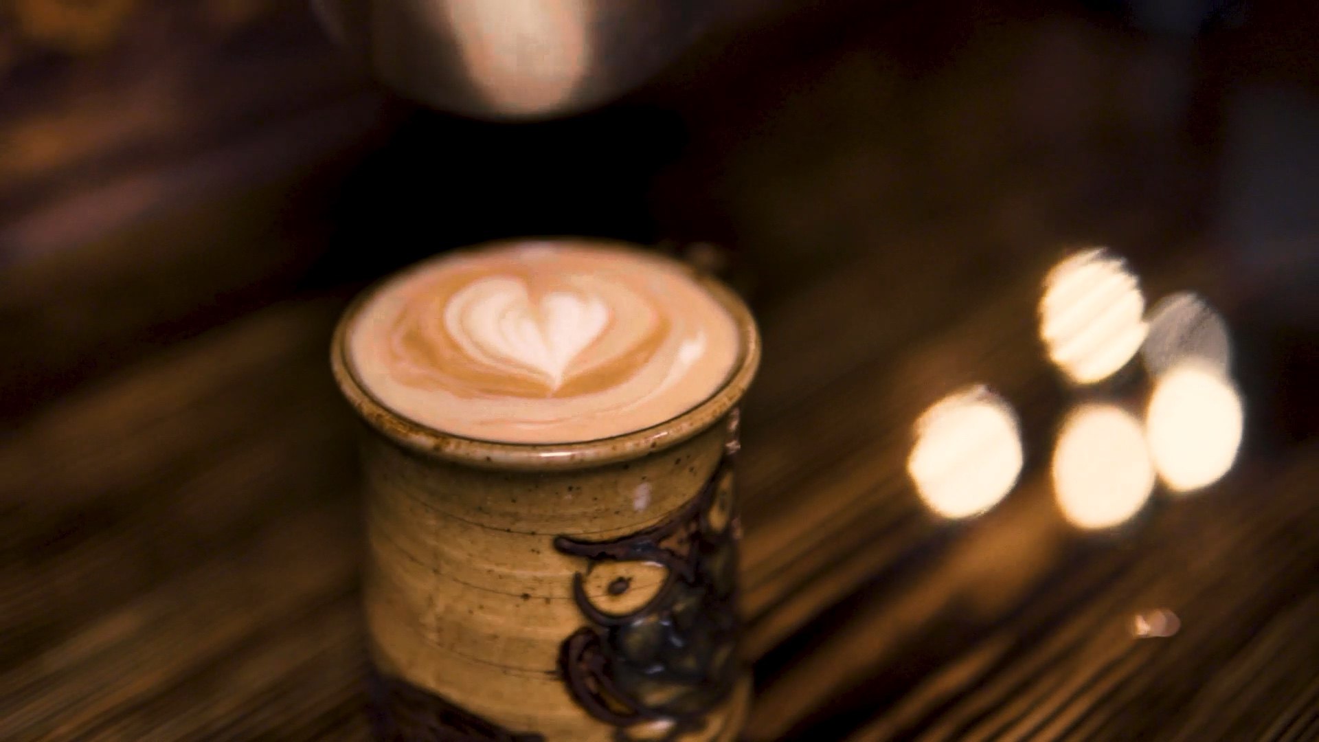 Latte with a heart in a handmade owl mug on the bar