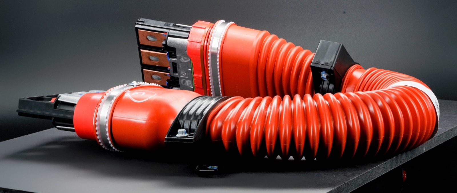Orange high-voltage busbar connector on a dark surface