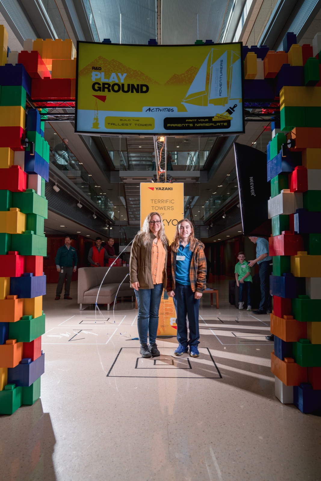 Families posing between giant toy-block columns at Kids Day