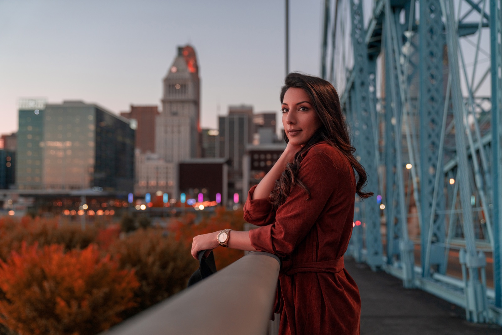 Woman leaning on a railing with the Cincinnati skyline behind her