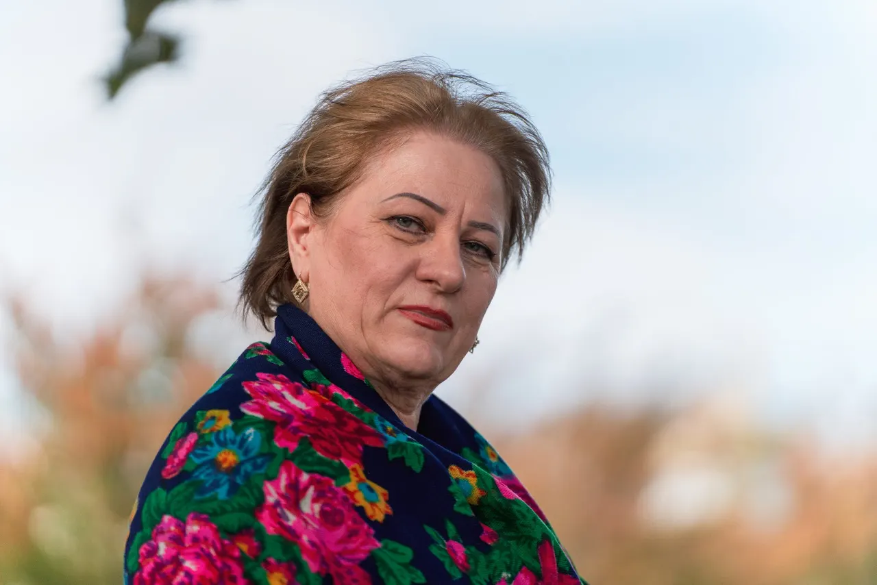 A woman in a flowered shawl, close up, against the sky