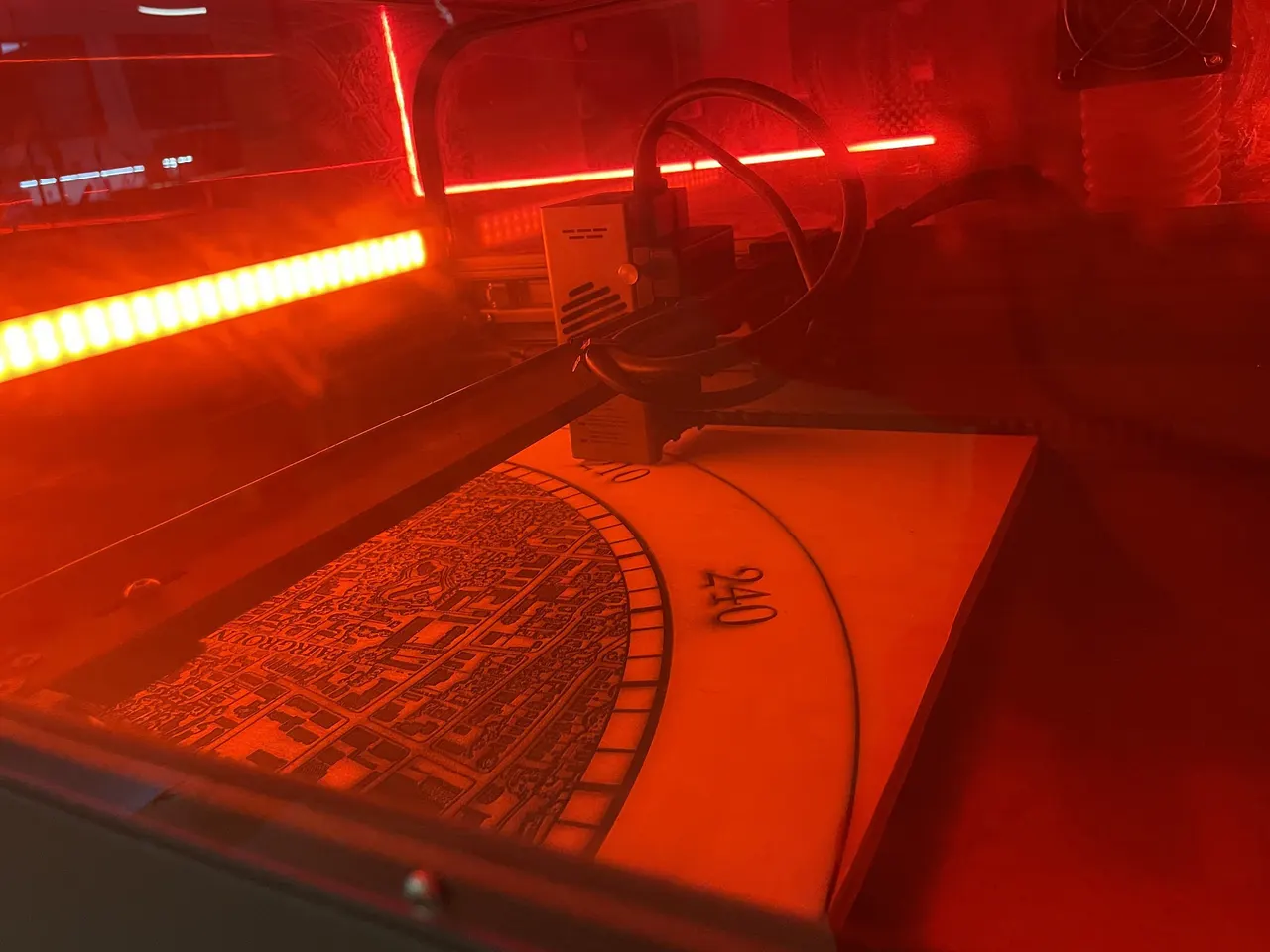 The street map being engraved inside a laser cutter, lit red