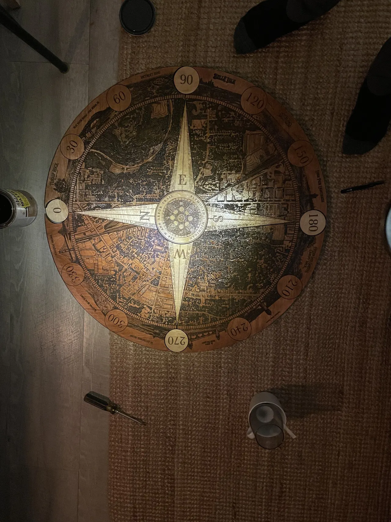 The compass topper stained a dark amber, lying on a wood floor