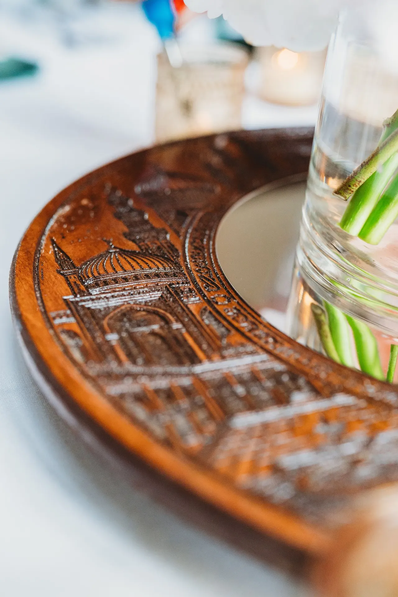 Close-up of engraved domes and towers on a wooden ring beside a glass vase
