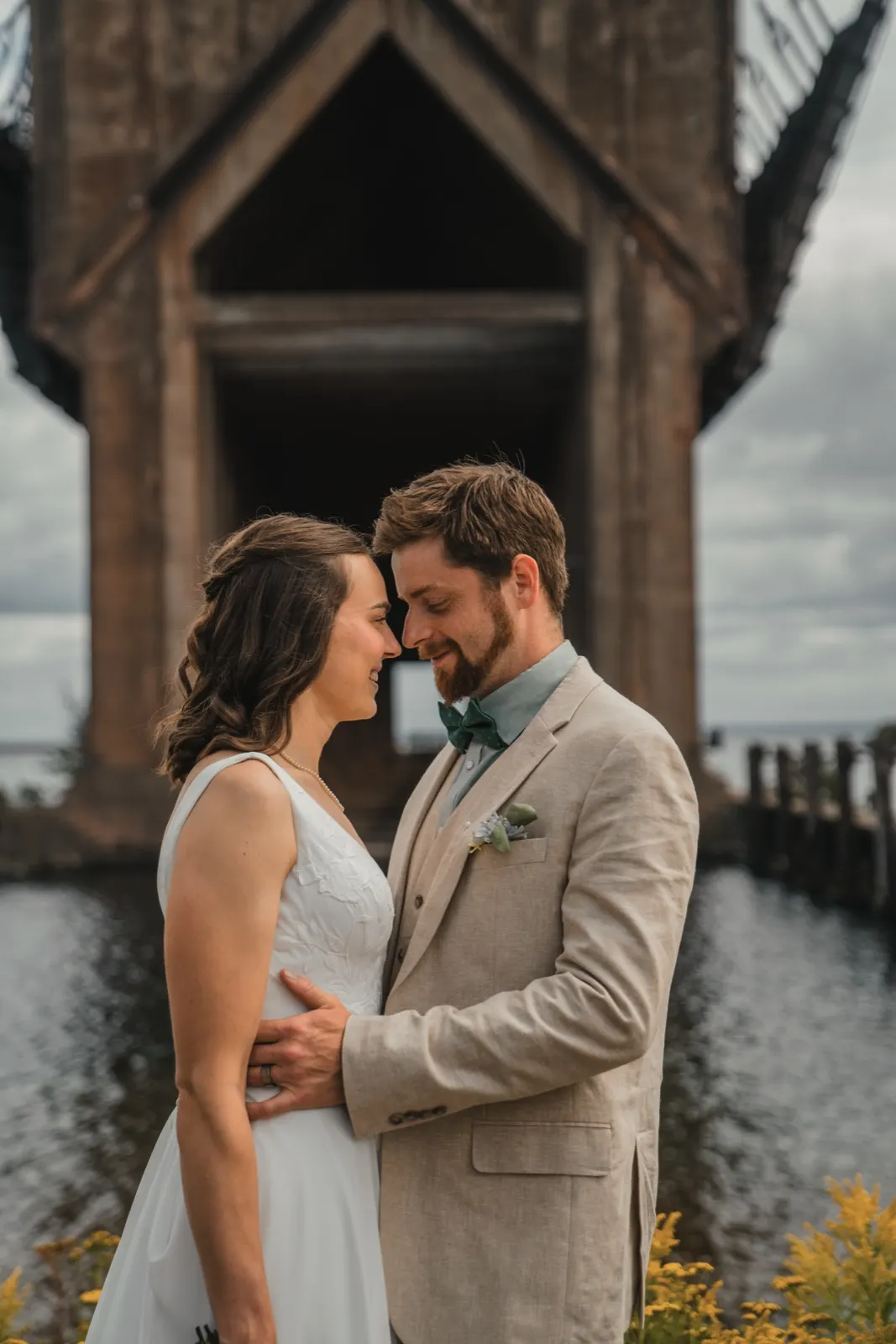 Bride and groom forehead to forehead by an old dock