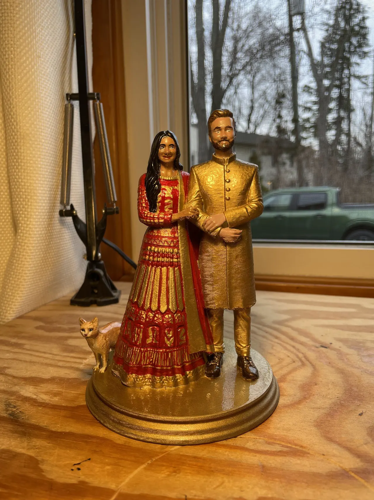 The finished topper painted in red and gold, standing on a wooden desk