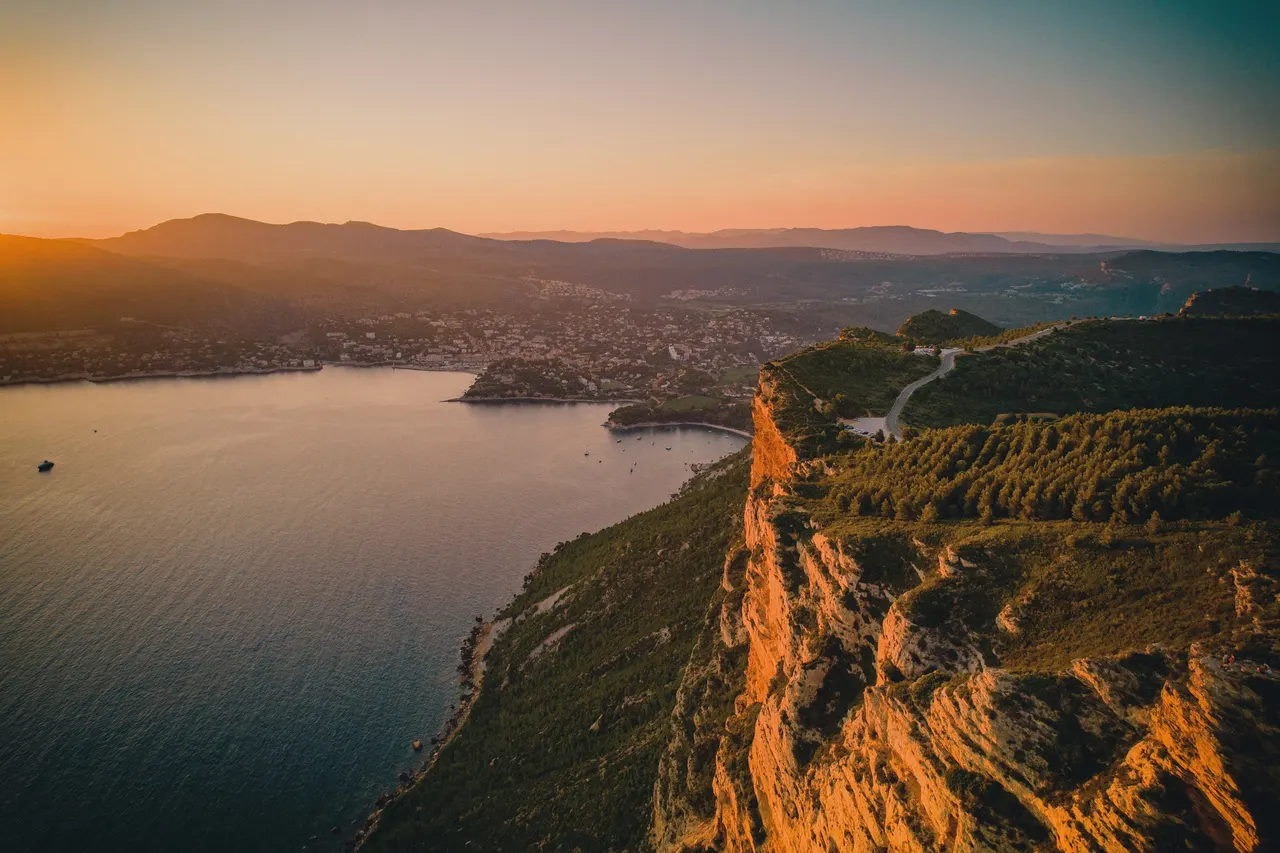 Sunset glowing on a long orange cliff above a calm bay