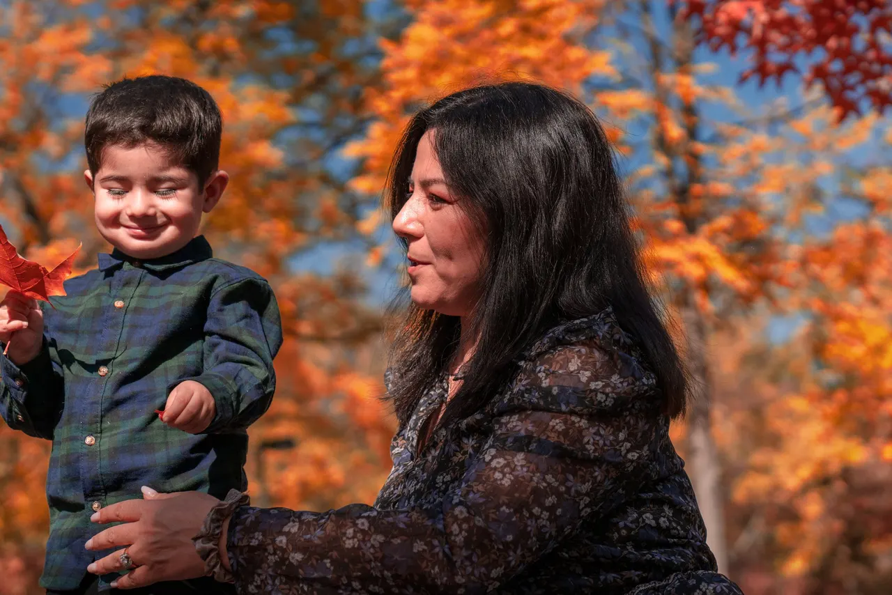 A little boy and his mother playing with red leaves