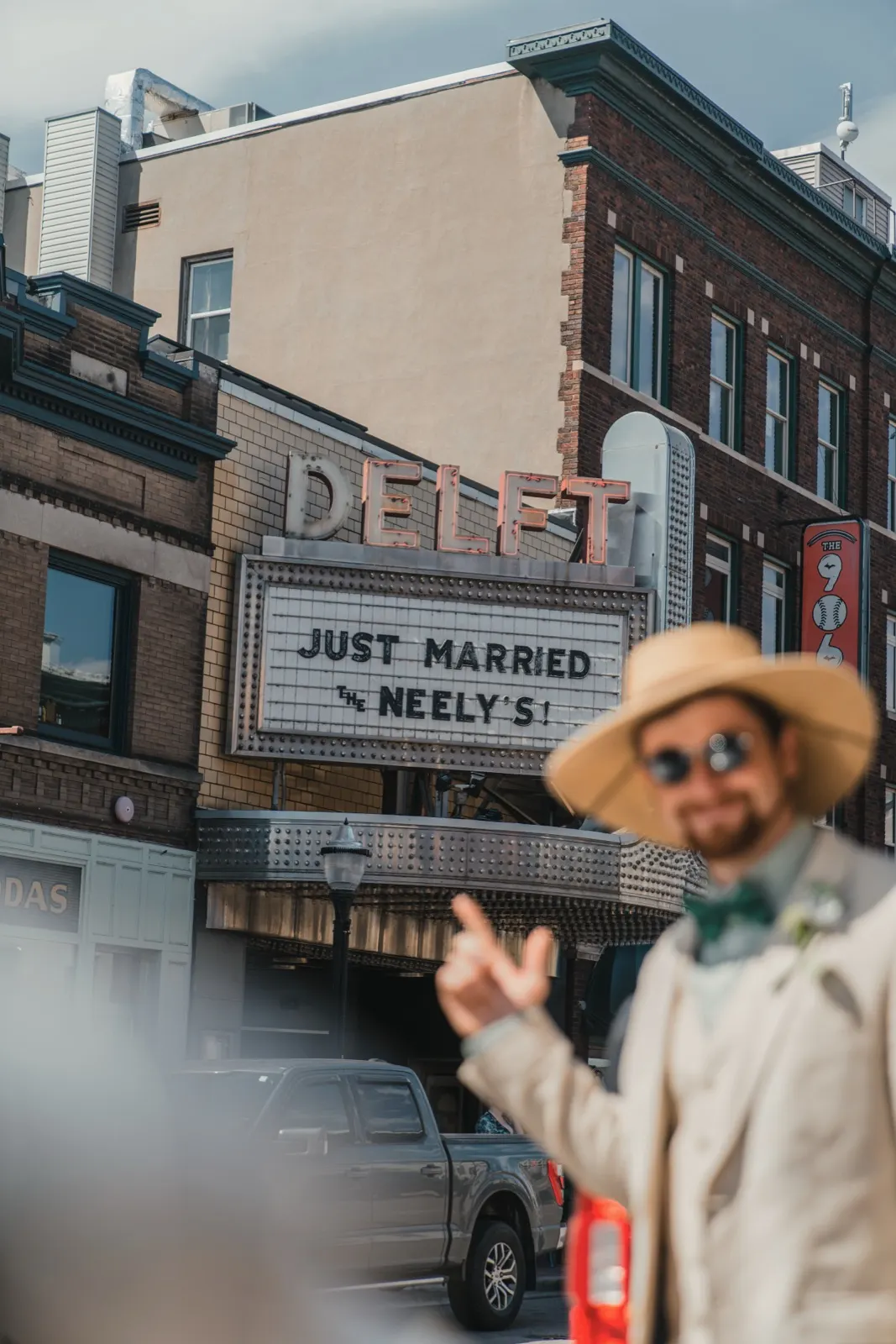 Groom in a straw hat pointing to a theater marquee