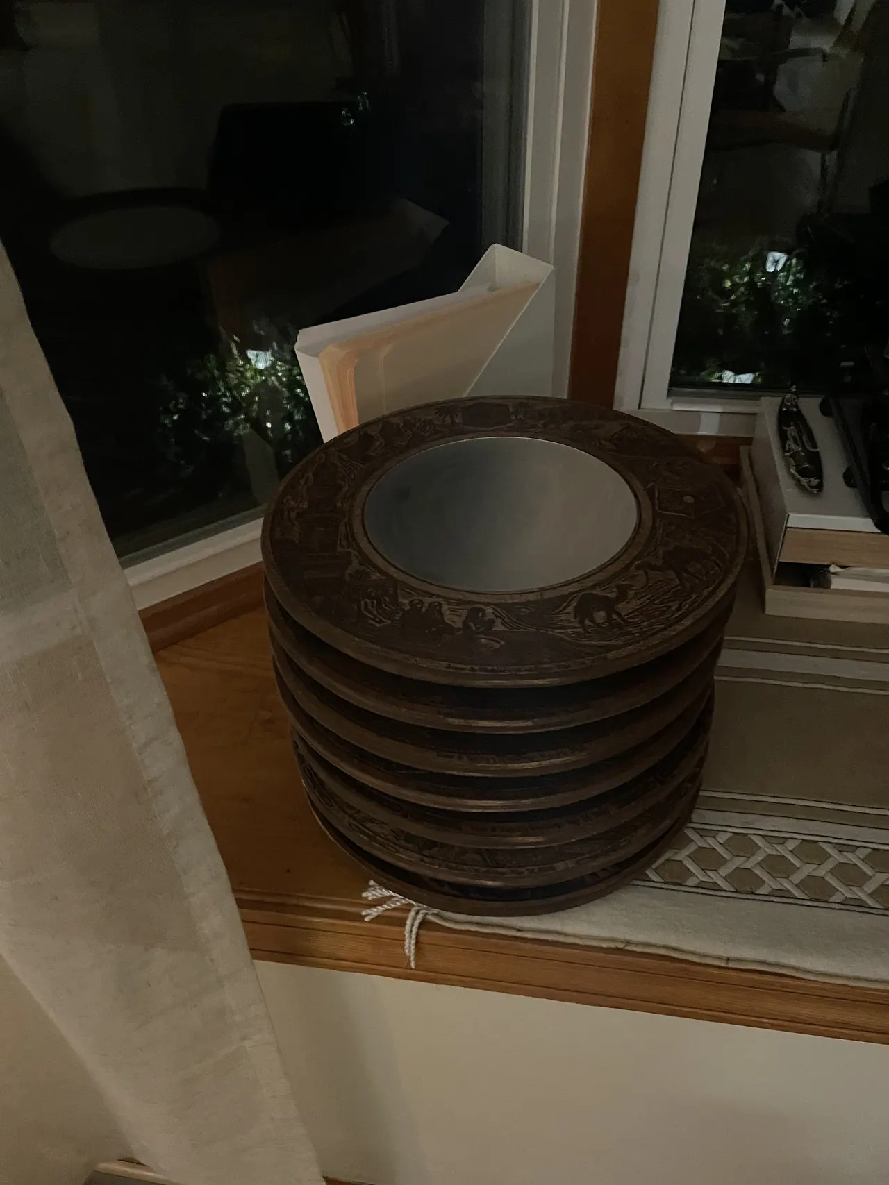 A stack of dark engraved wooden rings on a windowsill